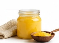 Jar of desi ghee with a wooden bowl and spoon