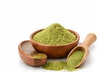 Wooden bowl of green wellness powder with a scoop